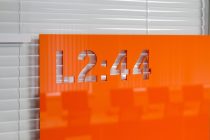 Laser cut room numbers in stencil typeface on orange acrylic